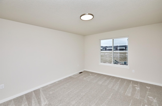 carpeted spare room featuring a textured ceiling