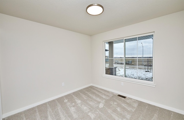 carpeted empty room featuring a textured ceiling