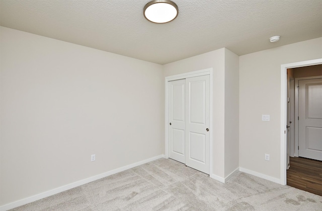 unfurnished bedroom with light colored carpet, a textured ceiling, and a closet