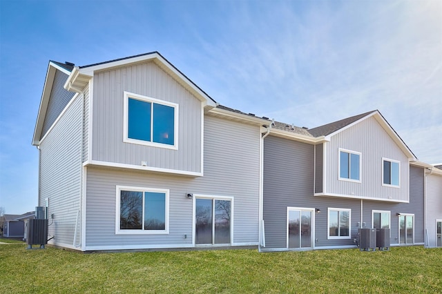 rear view of property featuring cooling unit and a lawn