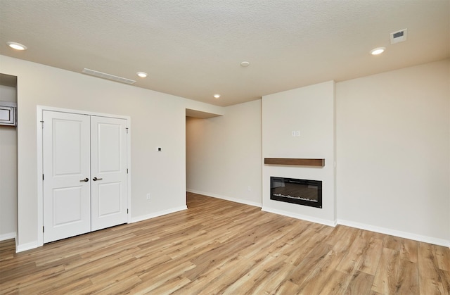 unfurnished living room featuring light hardwood / wood-style floors and a textured ceiling