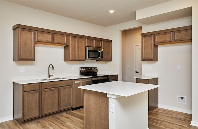 kitchen with light wood-type flooring, sink, a kitchen island, and appliances with stainless steel finishes