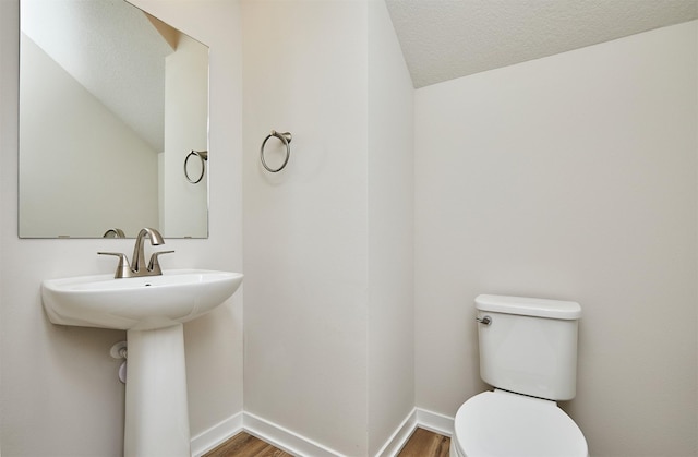 bathroom with hardwood / wood-style floors, a textured ceiling, and toilet