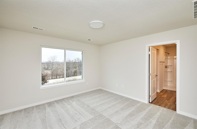 carpeted spare room with a textured ceiling