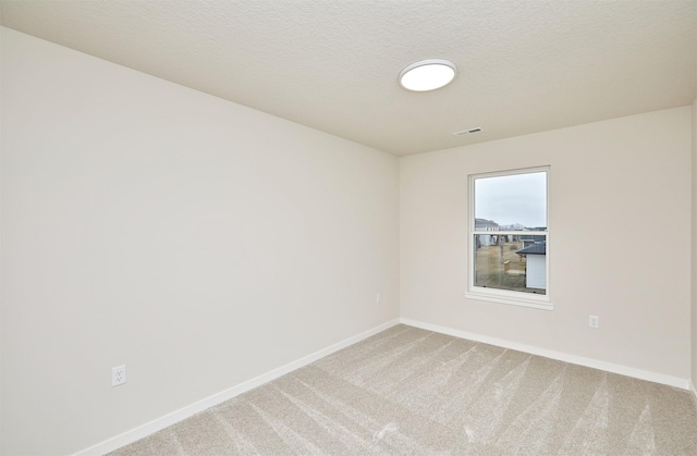 carpeted empty room with a textured ceiling