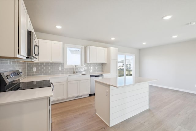 kitchen with white cabinets, a kitchen island, sink, and appliances with stainless steel finishes