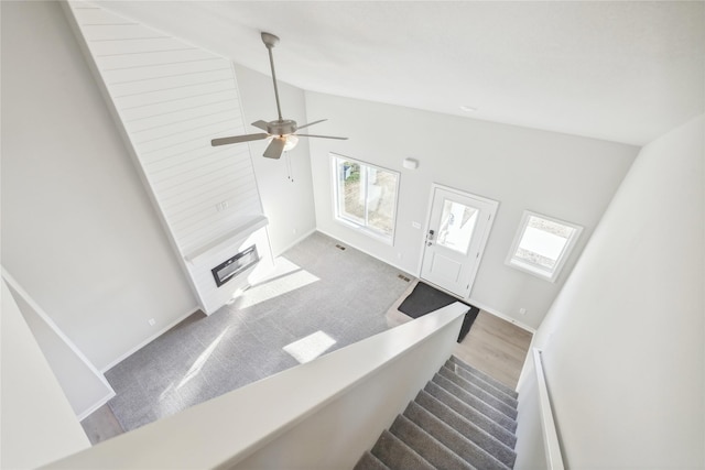 carpeted living room with ceiling fan, a healthy amount of sunlight, and high vaulted ceiling