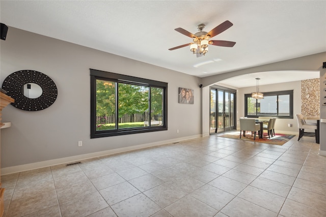 spare room featuring light tile patterned floors, baseboards, visible vents, arched walkways, and a ceiling fan