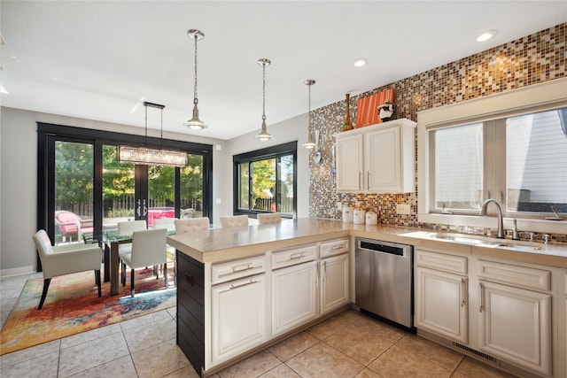 kitchen with a peninsula, a sink, light countertops, dishwasher, and pendant lighting