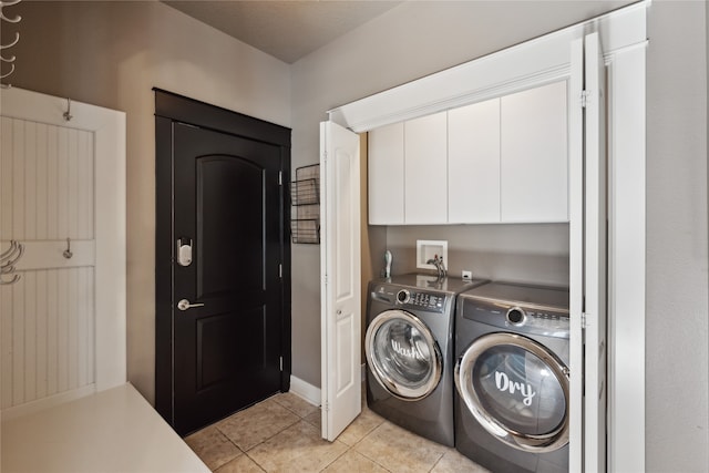 washroom with cabinet space, separate washer and dryer, and light tile patterned flooring