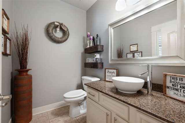 bathroom with toilet, tile patterned floors, baseboards, and vanity