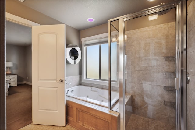 bathroom with a tub with jets, tile patterned flooring, and a shower stall