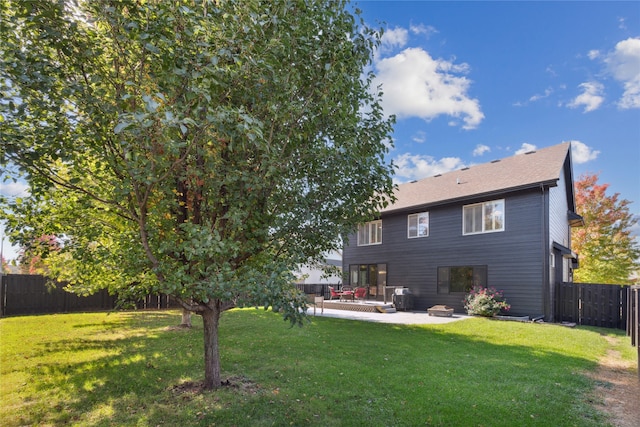 rear view of property with a fenced backyard, a yard, and a patio