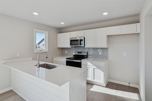 kitchen with white cabinetry, sink, kitchen peninsula, and appliances with stainless steel finishes