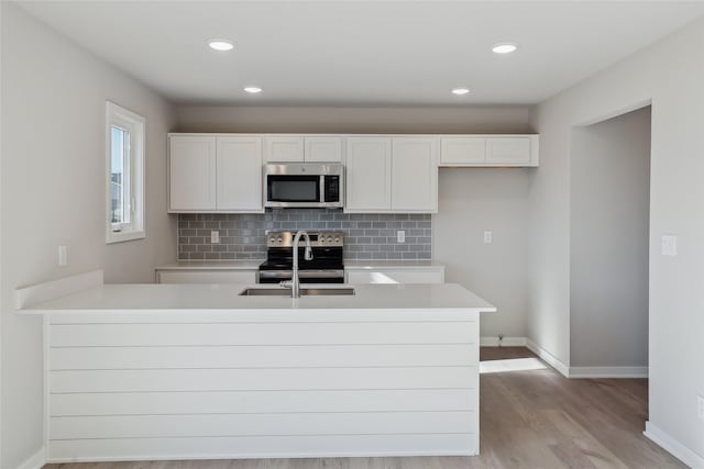 kitchen with sink, appliances with stainless steel finishes, kitchen peninsula, decorative backsplash, and white cabinets