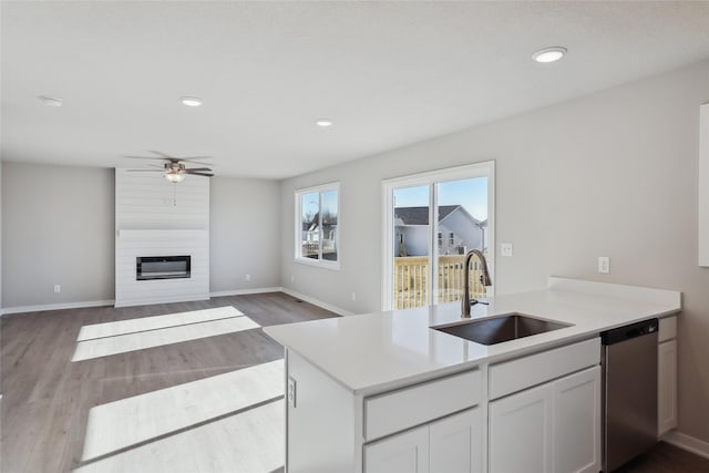 kitchen featuring sink, white cabinetry, a fireplace, stainless steel dishwasher, and kitchen peninsula