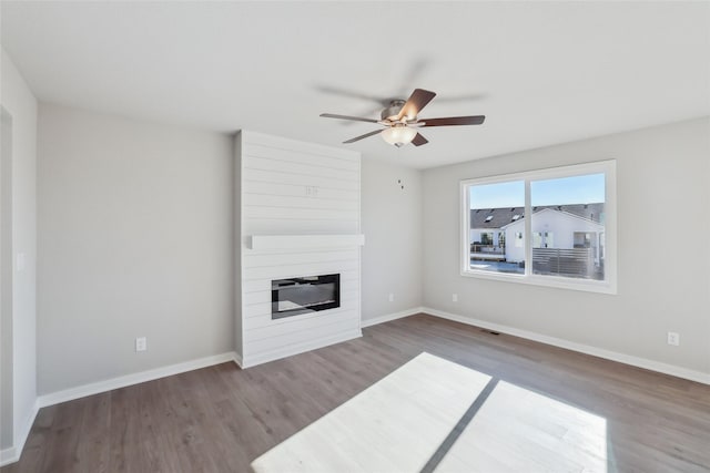 unfurnished living room featuring ceiling fan, dark hardwood / wood-style floors, and a fireplace