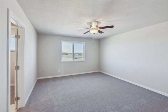 carpeted spare room featuring a textured ceiling and ceiling fan