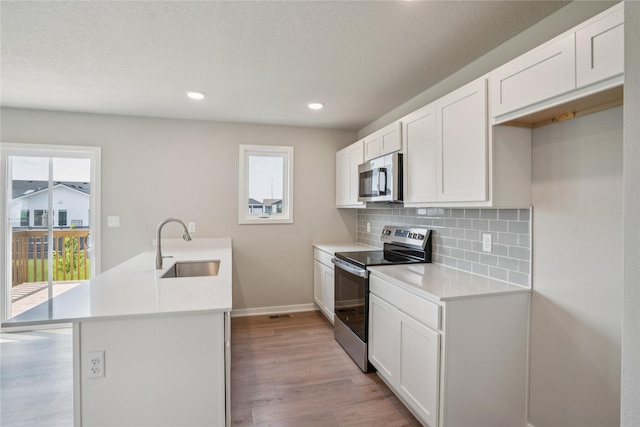 904 Spruce Ave, Norwalk, IA 50211 - kitchen with stainless steel appliances, a sink, light wood-type flooring, baseboards, and backsplash