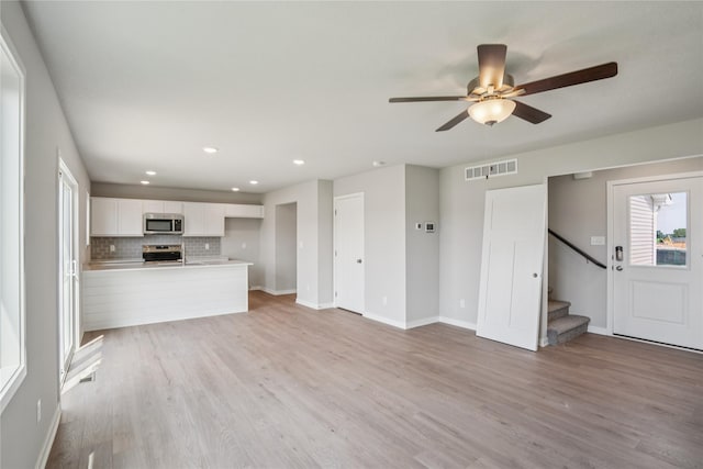 904 Spruce Ave, Norwalk, IA 50211 - unfurnished living room with light wood finished floors, ceiling fan, stairs, baseboards, and recessed lighting