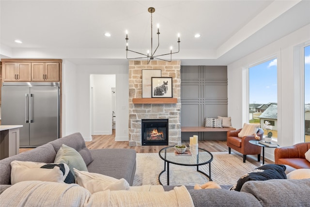 living room featuring a fireplace, a chandelier, and light wood-type flooring