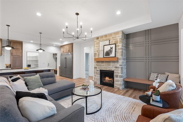 living room featuring a fireplace, light hardwood / wood-style flooring, and a notable chandelier