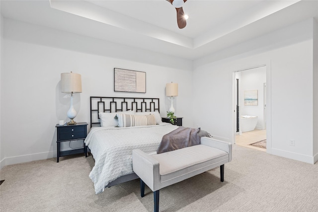 bedroom with ceiling fan, light carpet, connected bathroom, and a tray ceiling