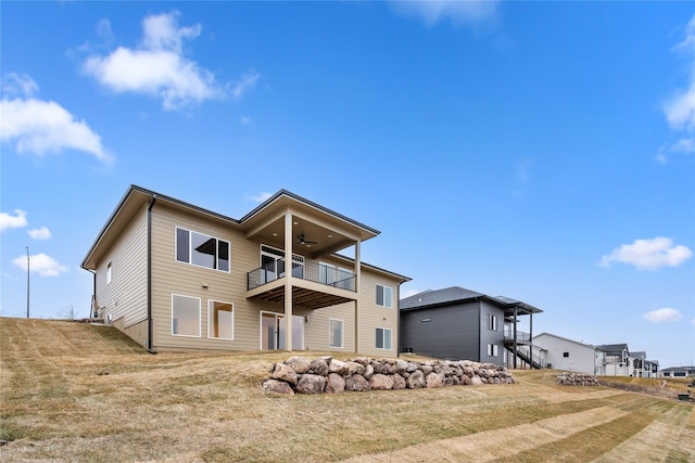 back of house featuring a balcony, ceiling fan, and a lawn