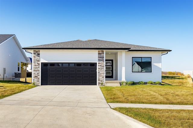 view of front of house featuring a front yard, cooling unit, and a garage