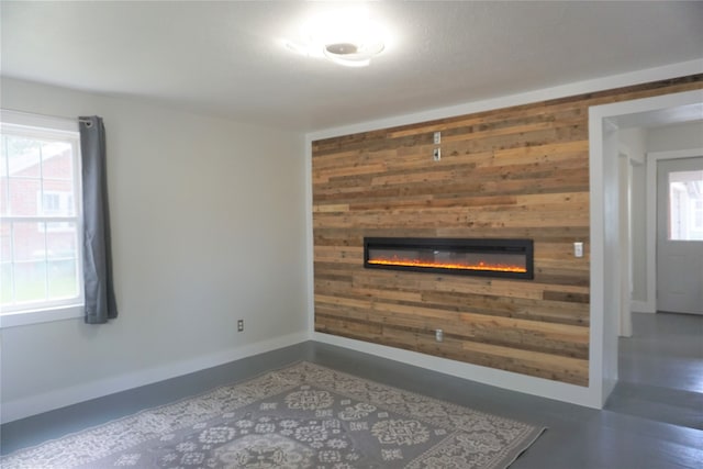 unfurnished living room featuring a healthy amount of sunlight and wooden walls