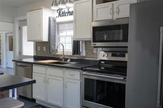 kitchen with appliances with stainless steel finishes, tasteful backsplash, hanging light fixtures, sink, and white cabinets