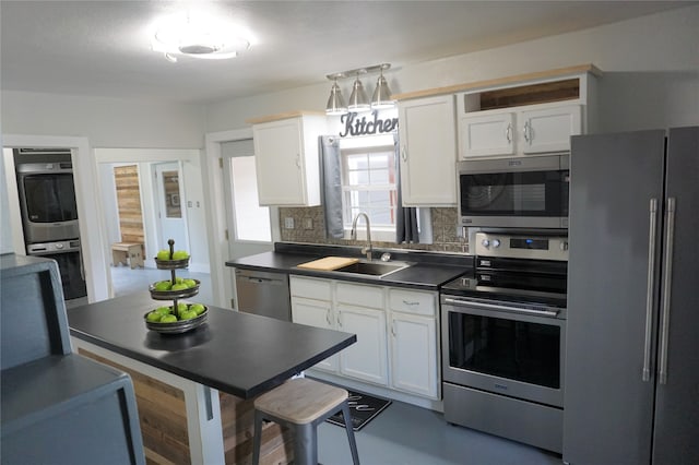 kitchen with stainless steel appliances, sink, white cabinetry, and tasteful backsplash