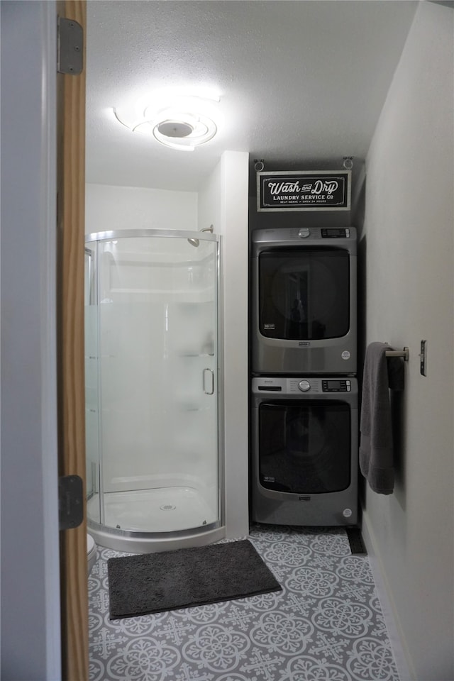 bathroom featuring stacked washer / dryer, a textured ceiling, and a shower with door