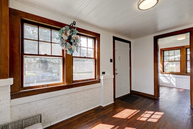 entryway with ornamental molding, dark hardwood / wood-style flooring, and brick wall