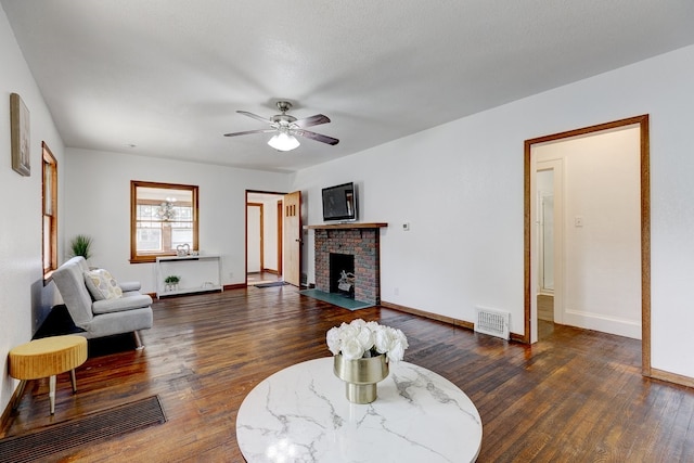 living room featuring ceiling fan, dark hardwood / wood-style flooring, a textured ceiling, and a brick fireplace