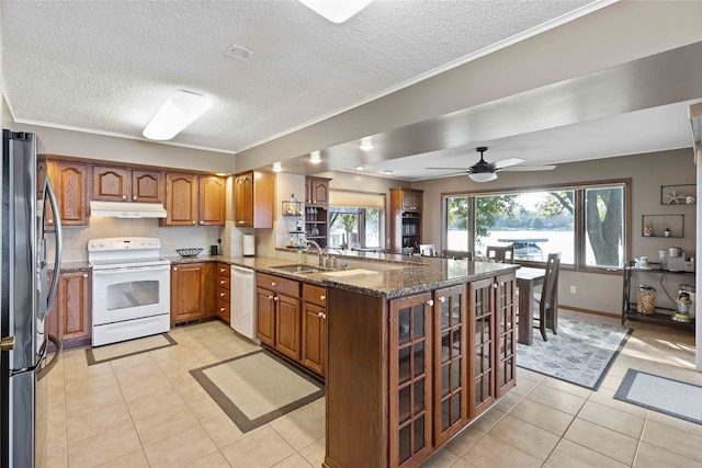 kitchen with white appliances, dark stone countertops, kitchen peninsula, ceiling fan, and light tile patterned flooring