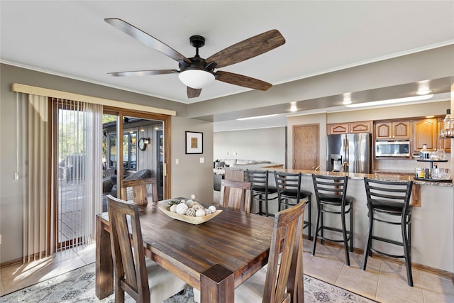 dining room with ceiling fan, ornamental molding, and light tile patterned flooring