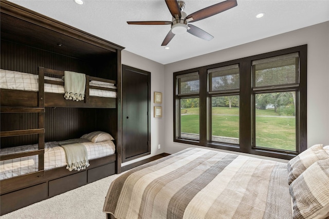 carpeted bedroom featuring ceiling fan and a textured ceiling