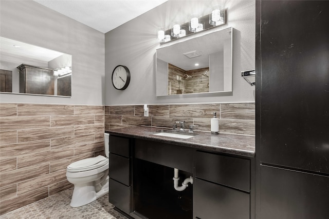 bathroom featuring vanity, toilet, tile walls, and decorative backsplash