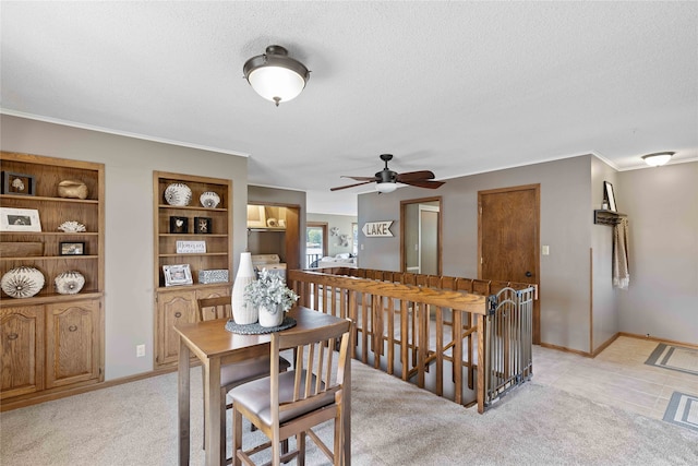 dining area with a textured ceiling, ceiling fan, ornamental molding, and light carpet