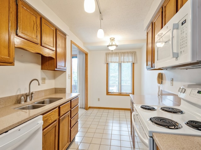 kitchen with light tile patterned floors, white appliances, sink, pendant lighting, and a textured ceiling