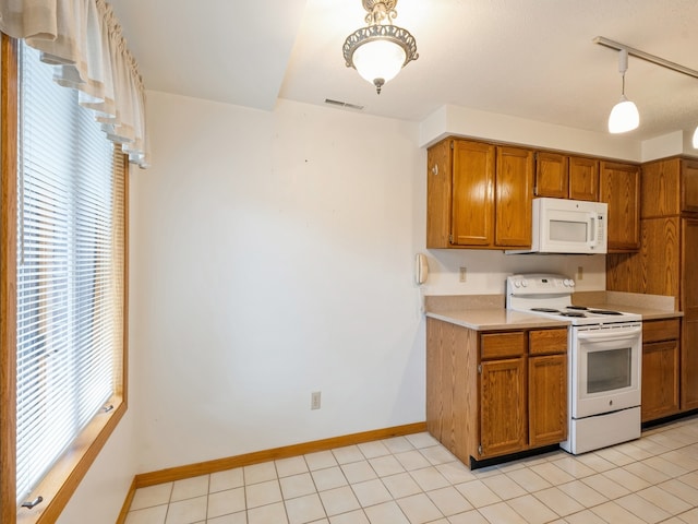 kitchen featuring decorative light fixtures, white appliances, and light tile patterned floors