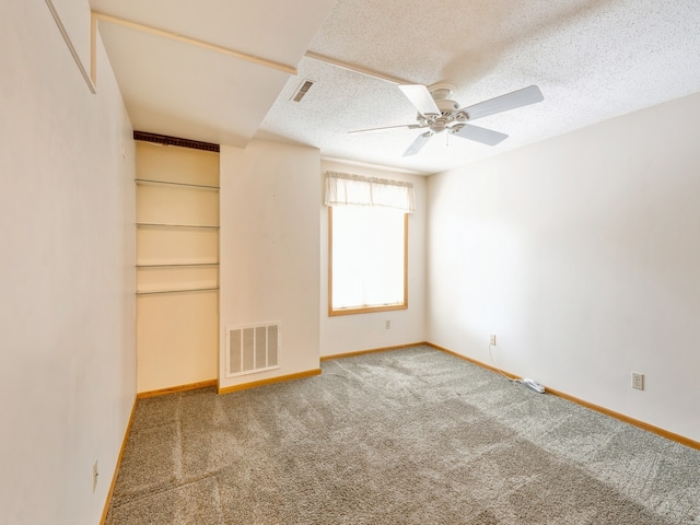 empty room featuring ceiling fan, carpet floors, and a textured ceiling