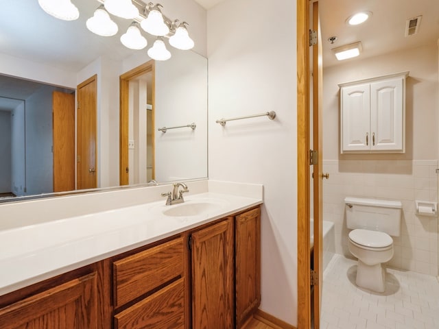 bathroom with tile patterned floors, toilet, a bath, tile walls, and vanity