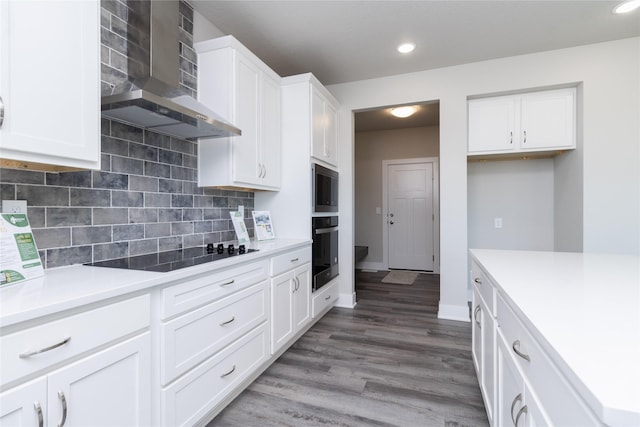 kitchen with tasteful backsplash, wood-type flooring, white cabinets, black electric cooktop, and wall chimney exhaust hood