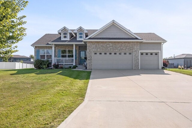 view of front of house featuring covered porch, a garage, and a front yard