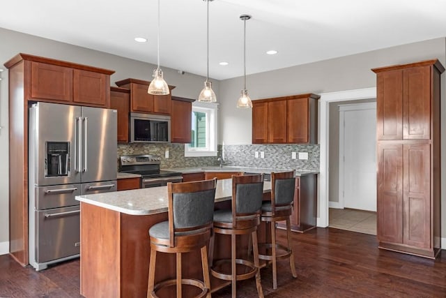 kitchen with tasteful backsplash, appliances with stainless steel finishes, dark wood-type flooring, a center island, and light countertops