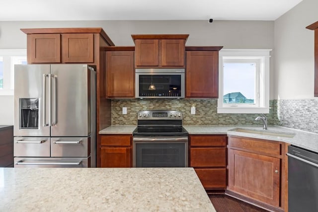 kitchen with tasteful backsplash, appliances with stainless steel finishes, brown cabinetry, and a sink