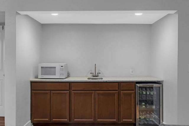 bar with white microwave, wine cooler, wet bar, and a sink