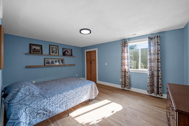 bedroom with visible vents, baseboards, and wood finished floors